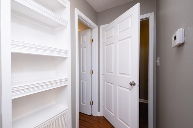 hallway featuring dark hardwood / wood-style floors and a textured ceiling