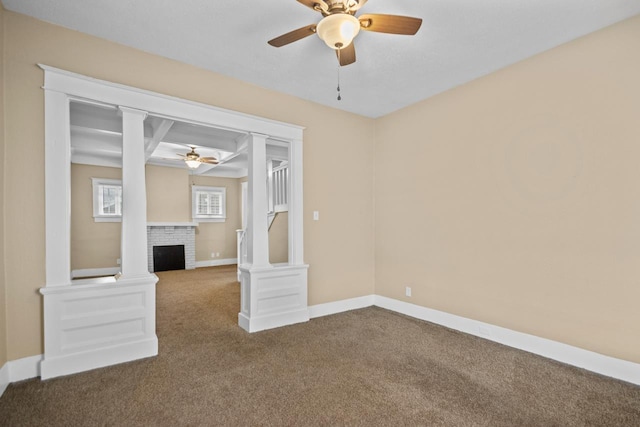 empty room featuring a fireplace, decorative columns, ceiling fan, and carpet