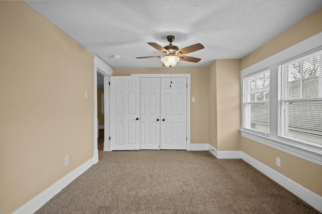 unfurnished bedroom featuring ceiling fan, a closet, a textured ceiling, and carpet