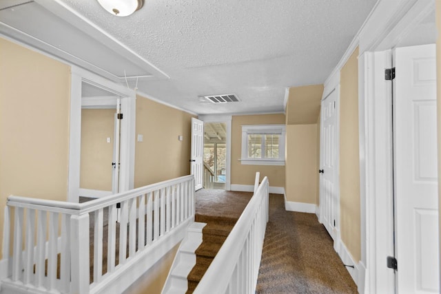 corridor with crown molding, dark carpet, and a textured ceiling