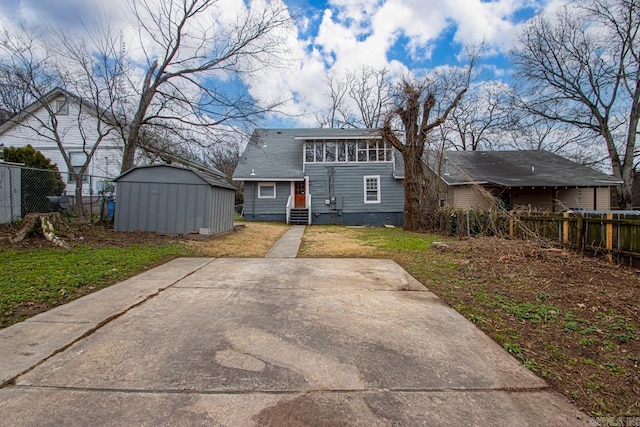 rear view of property with a shed and a patio area