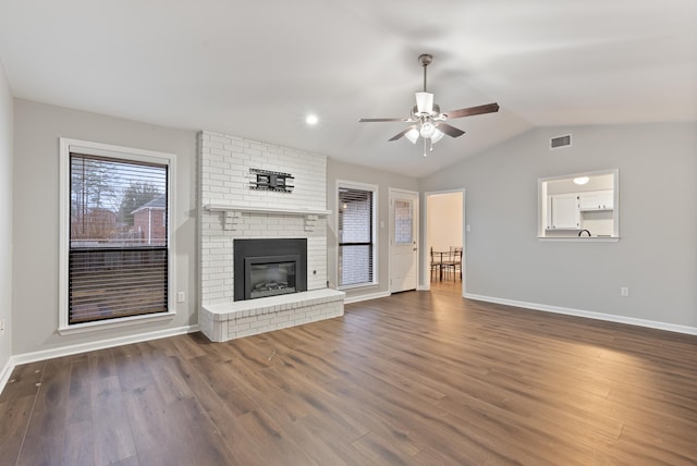 unfurnished living room with vaulted ceiling, dark wood-type flooring, ceiling fan, and a fireplace