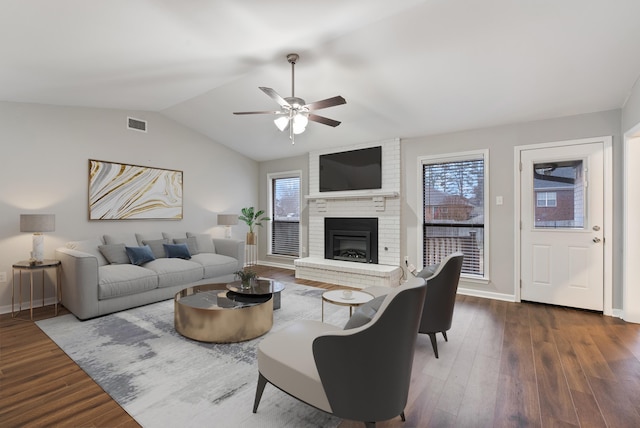 living room featuring lofted ceiling, a fireplace, dark wood-type flooring, and plenty of natural light