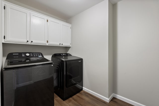 clothes washing area with separate washer and dryer, dark hardwood / wood-style floors, and cabinets