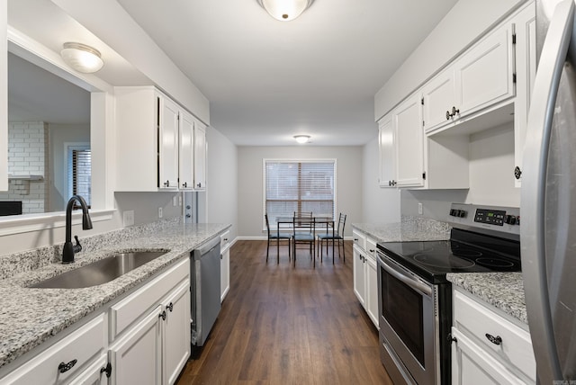 kitchen with appliances with stainless steel finishes, sink, white cabinets, light stone countertops, and dark wood-type flooring