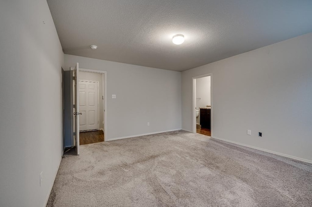 unfurnished bedroom with connected bathroom, a textured ceiling, and carpet