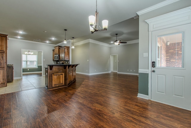 kitchen with pendant lighting, dark wood-type flooring, a breakfast bar area, ornamental molding, and ceiling fan with notable chandelier