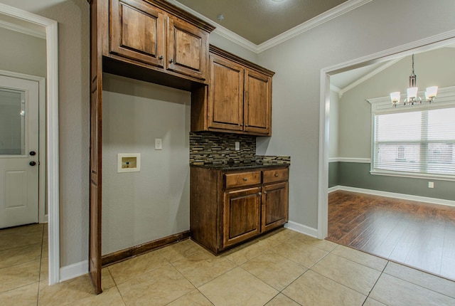 kitchen featuring light tile patterned floors, backsplash, ornamental molding, vaulted ceiling, and a chandelier