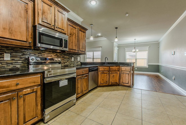 kitchen featuring light tile patterned flooring, decorative light fixtures, sink, ornamental molding, and stainless steel appliances