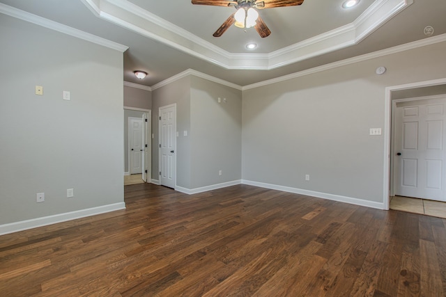 empty room with a raised ceiling, ornamental molding, dark hardwood / wood-style floors, and ceiling fan