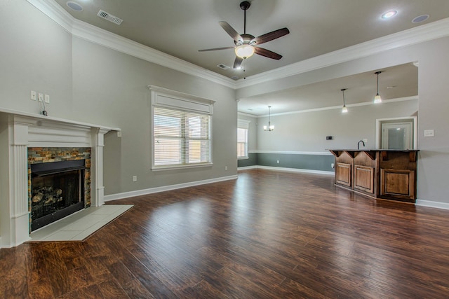 unfurnished living room featuring a tile fireplace, sink, ornamental molding, ceiling fan, and dark wood-type flooring