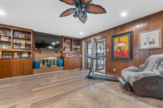 interior space with ceiling fan, light hardwood / wood-style floors, and wood walls