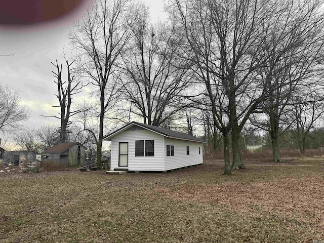 view of side of home with a storage shed and a yard