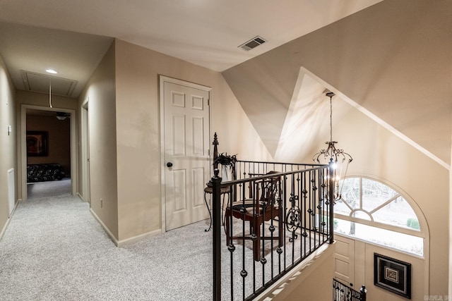 corridor featuring light carpet and a notable chandelier