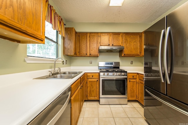 kitchen with appliances with stainless steel finishes, sink, a textured ceiling, and light tile patterned floors