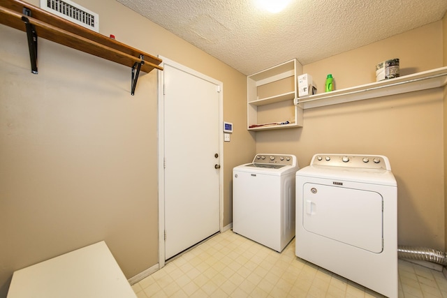 clothes washing area with washer and clothes dryer and a textured ceiling