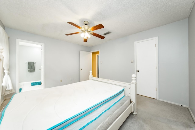 bedroom with light carpet, ceiling fan, a textured ceiling, and ensuite bathroom