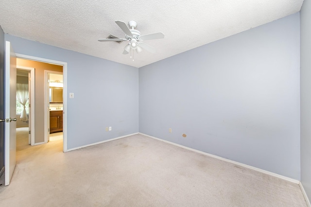 carpeted spare room featuring ceiling fan and a textured ceiling