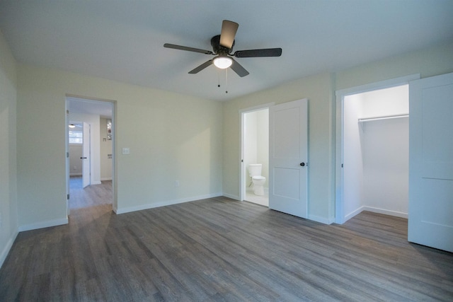 unfurnished bedroom featuring dark wood-type flooring, ceiling fan, connected bathroom, and a spacious closet