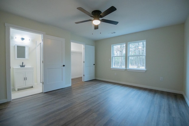 unfurnished bedroom with ceiling fan, a spacious closet, sink, and hardwood / wood-style floors