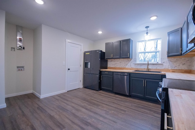 kitchen with decorative light fixtures, dishwasher, butcher block counters, sink, and black fridge