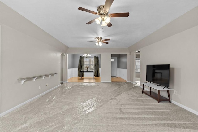 unfurnished living room featuring ceiling fan with notable chandelier