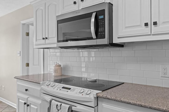 kitchen featuring tasteful backsplash, white cabinets, light stone counters, and electric stove