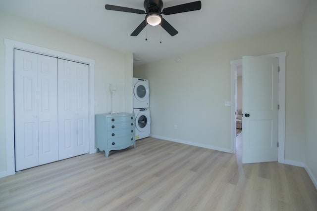 washroom featuring stacked washer and clothes dryer, ceiling fan, and light hardwood / wood-style flooring