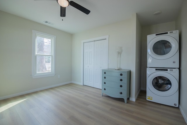 laundry room with stacked washer / drying machine, ceiling fan, and light wood-type flooring