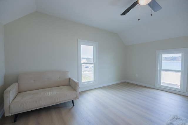 living area with ceiling fan, light hardwood / wood-style floors, vaulted ceiling, and a wealth of natural light