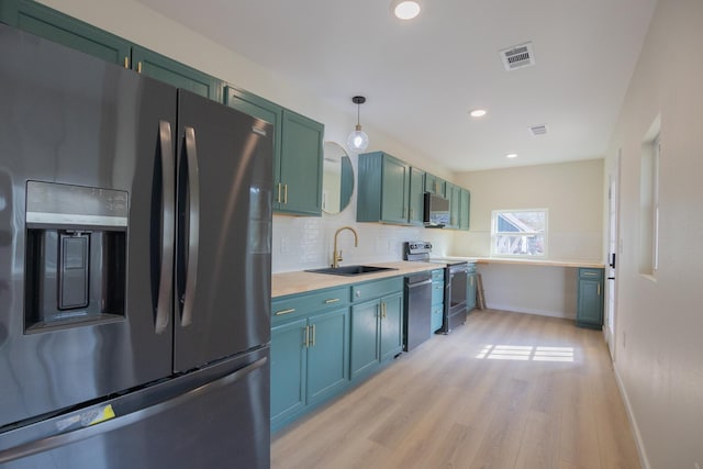 kitchen with sink, tasteful backsplash, green cabinetry, decorative light fixtures, and appliances with stainless steel finishes