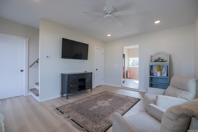 living room with light hardwood / wood-style flooring and ceiling fan