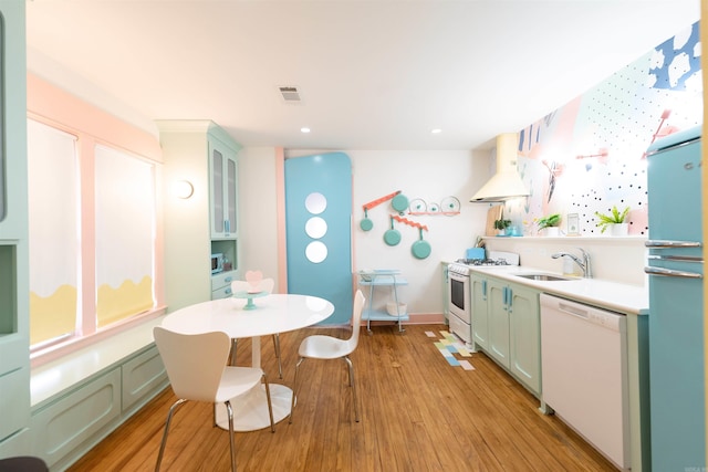 kitchen featuring white appliances, light hardwood / wood-style floors, sink, and custom exhaust hood