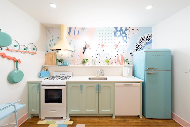 kitchen featuring sink, light wood-type flooring, green cabinets, custom range hood, and white appliances