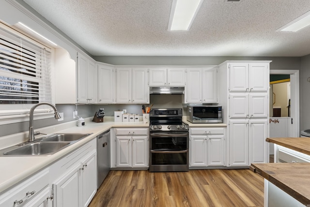 kitchen featuring white cabinetry, sink, light wood-type flooring, stainless steel appliances, and a textured ceiling