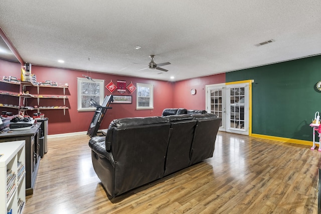 living room with hardwood / wood-style floors, a textured ceiling, and ceiling fan