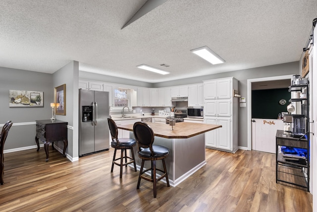 kitchen featuring stainless steel appliances, a kitchen island, and white cabinets