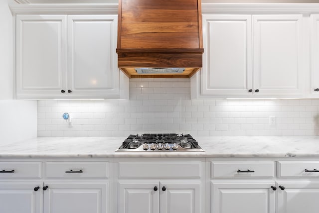 kitchen featuring white cabinets, decorative backsplash, light stone countertops, and stainless steel gas stovetop