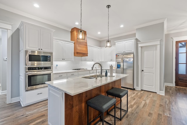 kitchen with sink, a center island with sink, stainless steel appliances, light stone countertops, and white cabinets