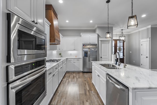 kitchen featuring stainless steel appliances, an island with sink, sink, and white cabinets