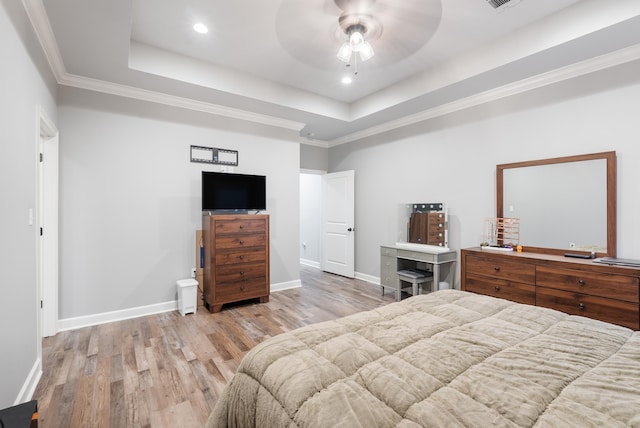 bedroom with crown molding, light hardwood / wood-style flooring, a raised ceiling, and ceiling fan