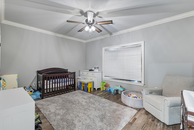 bedroom featuring hardwood / wood-style floors, a crib, and ornamental molding