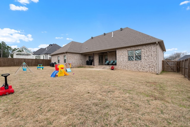 back of property with a lawn and a playground