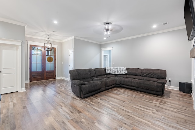 living room featuring ornamental molding, ceiling fan with notable chandelier, and light hardwood / wood-style floors