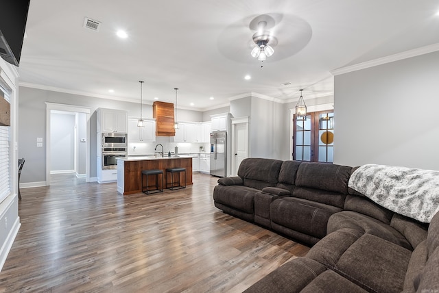 living room featuring hardwood / wood-style flooring, ornamental molding, and sink