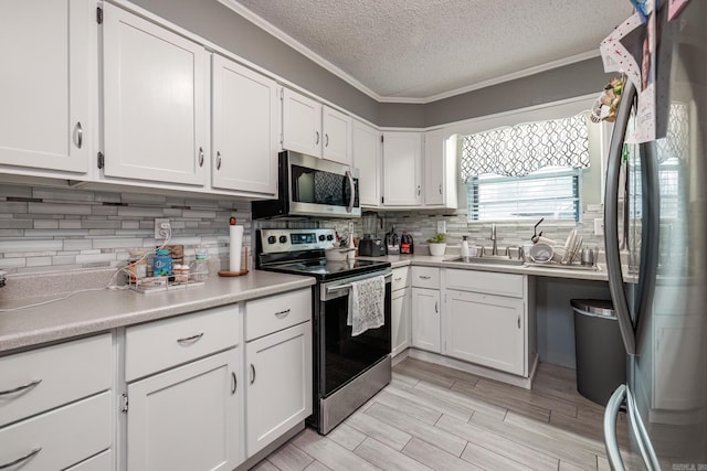 kitchen with backsplash, stainless steel appliances, sink, and white cabinets