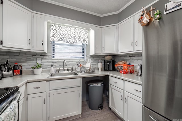 kitchen with white cabinetry, appliances with stainless steel finishes, sink, and ornamental molding