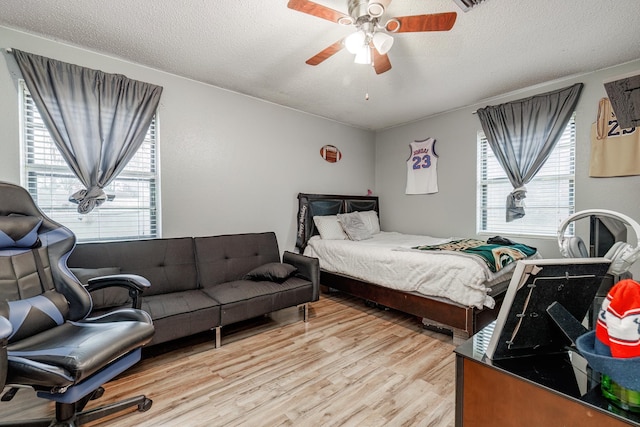 bedroom with multiple windows, ceiling fan, a textured ceiling, and light wood-type flooring