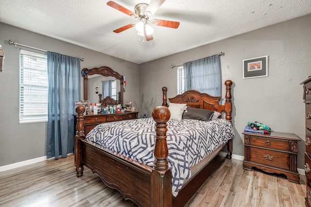 bedroom with ceiling fan, a textured ceiling, and light hardwood / wood-style flooring