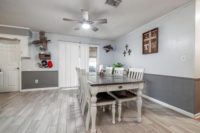 dining area with ceiling fan, crown molding, and a textured ceiling